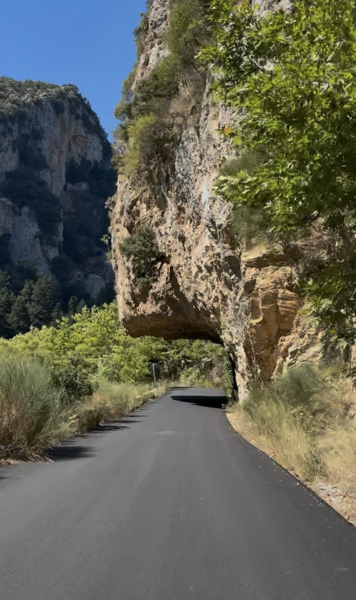 The narrow mountain road through the Langada Pass beneath an overhanging cliff