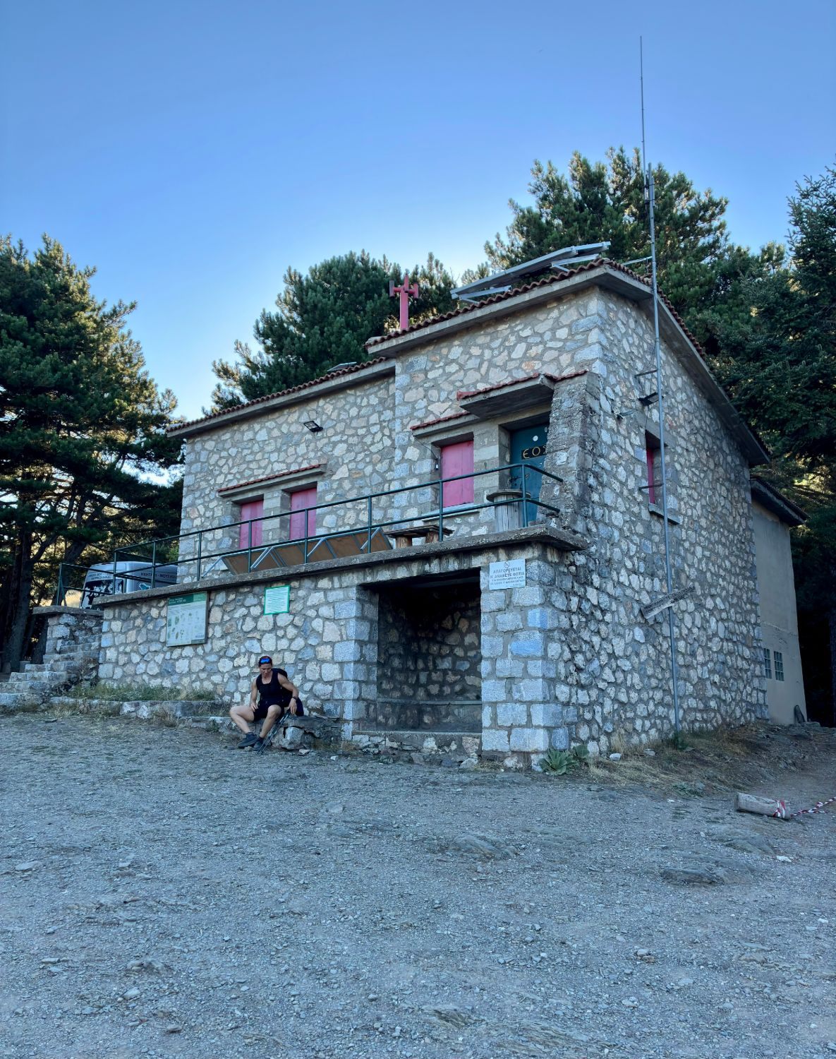 Kristine resting outside the stone-built Taygetos Refuge among the pines