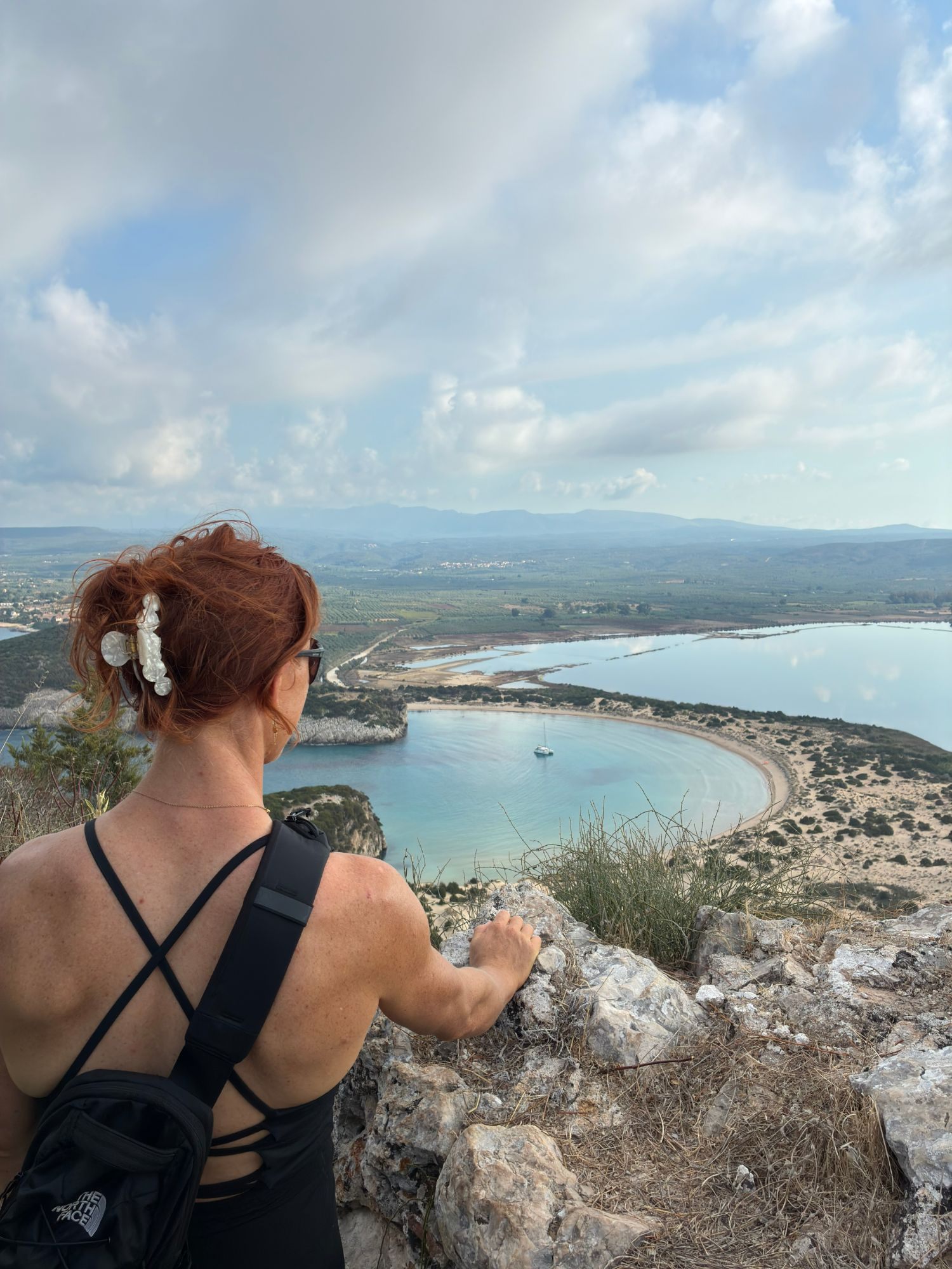 Kristine looking down from the rocks at the turquoise bay of Voidokilia and the lagoon