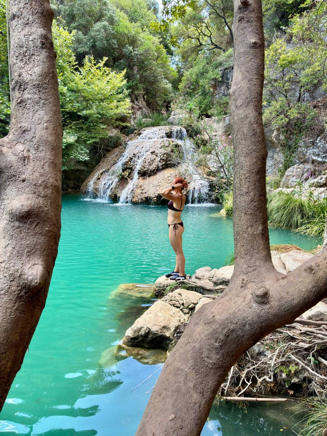 Kristine standing on a rock at the edge of the Kadi pool in front of Kadi Waterfall